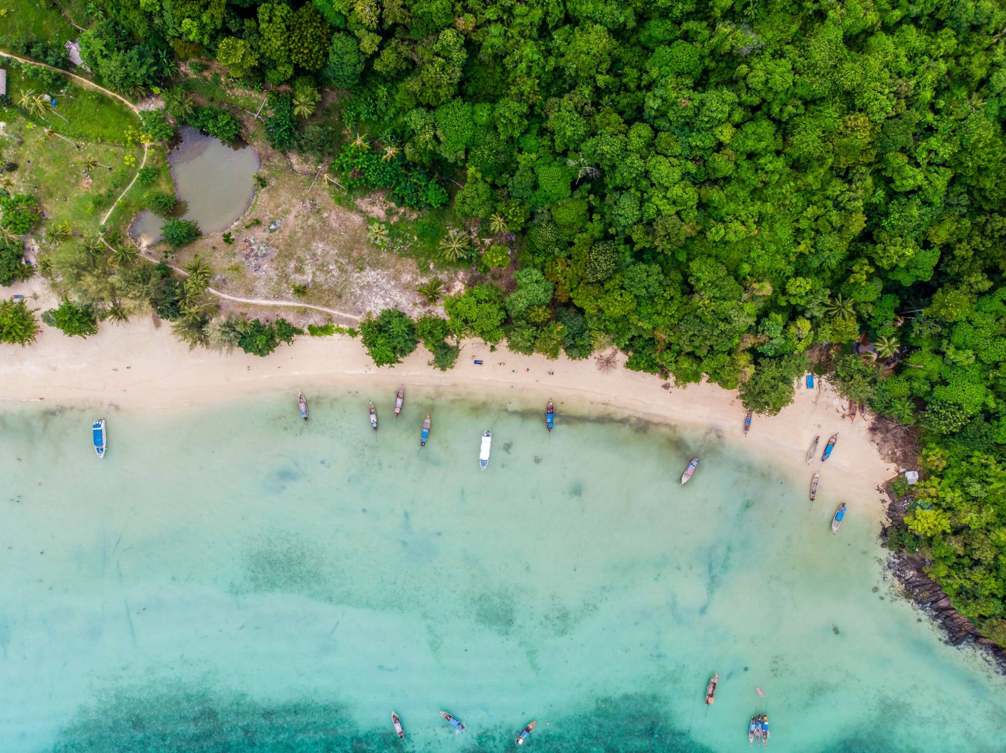Aerial view of Bamboo Island beach with longtail boats along the shore